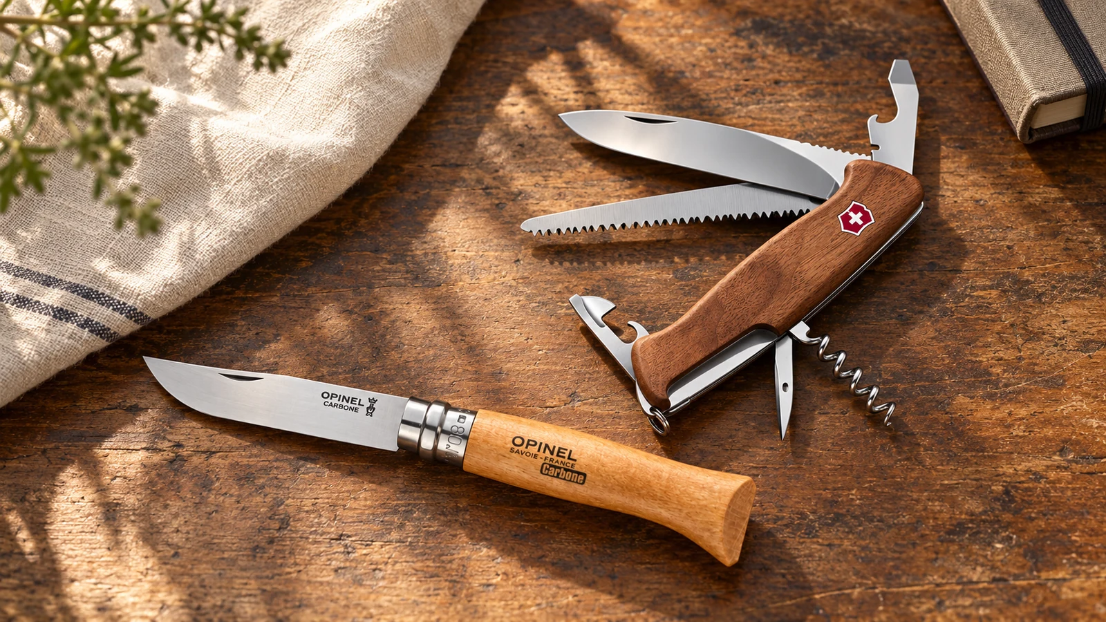 Un Opinel N°08 Carbone et un Victorinox Ranger 55 Wood actuels, sur une table en bois.