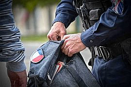 policier qui controle le sac d'un homme à la recherche d'un éventuel couteau