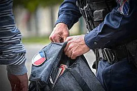 policier qui controle le sac d'un homme à la recherche d'un éventuel couteau
