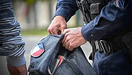 policier qui controle le sac d'un homme à la recherche d'un éventuel couteau